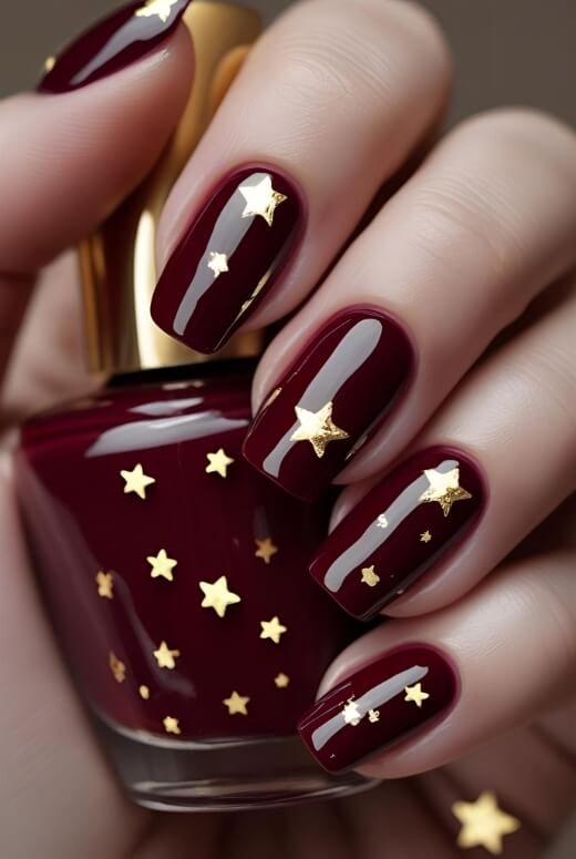 Image of Elegant deep red nails with delicate gold star accents Elegant deep red nails with delicate gold star accents